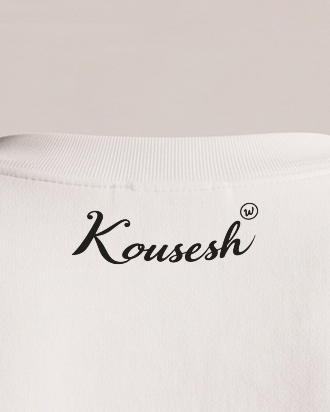 Close-up of the back collar, with Kousesh in script following the curve of the neckline and a small circled W